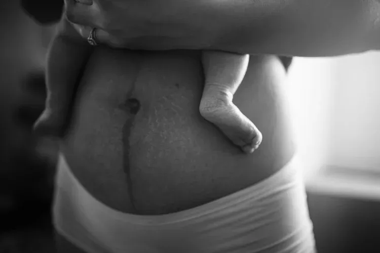 Mother holding her newborn in a black and white portrait