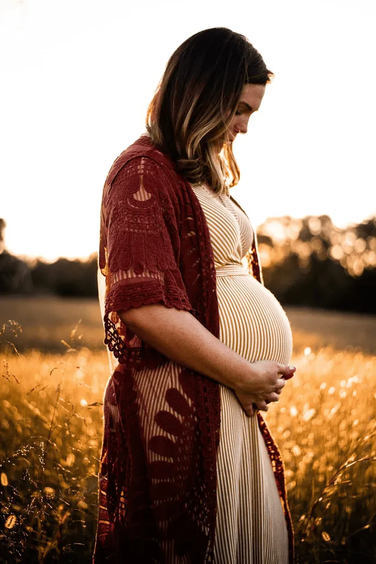 Pregnant woman cradling her belly at golden hour